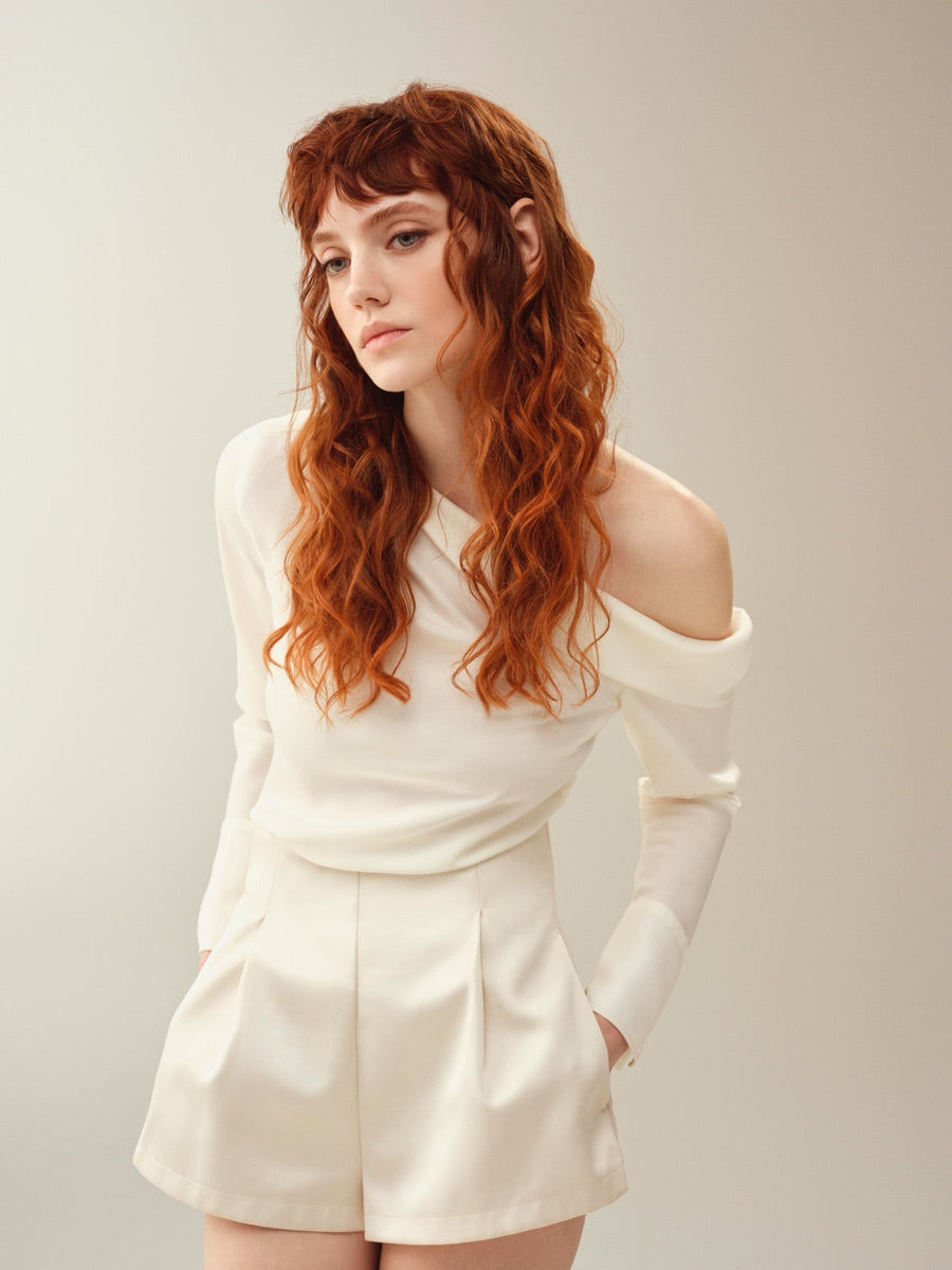 Modelo de cabello largo cobrizo con flequillo sobre fondo crema