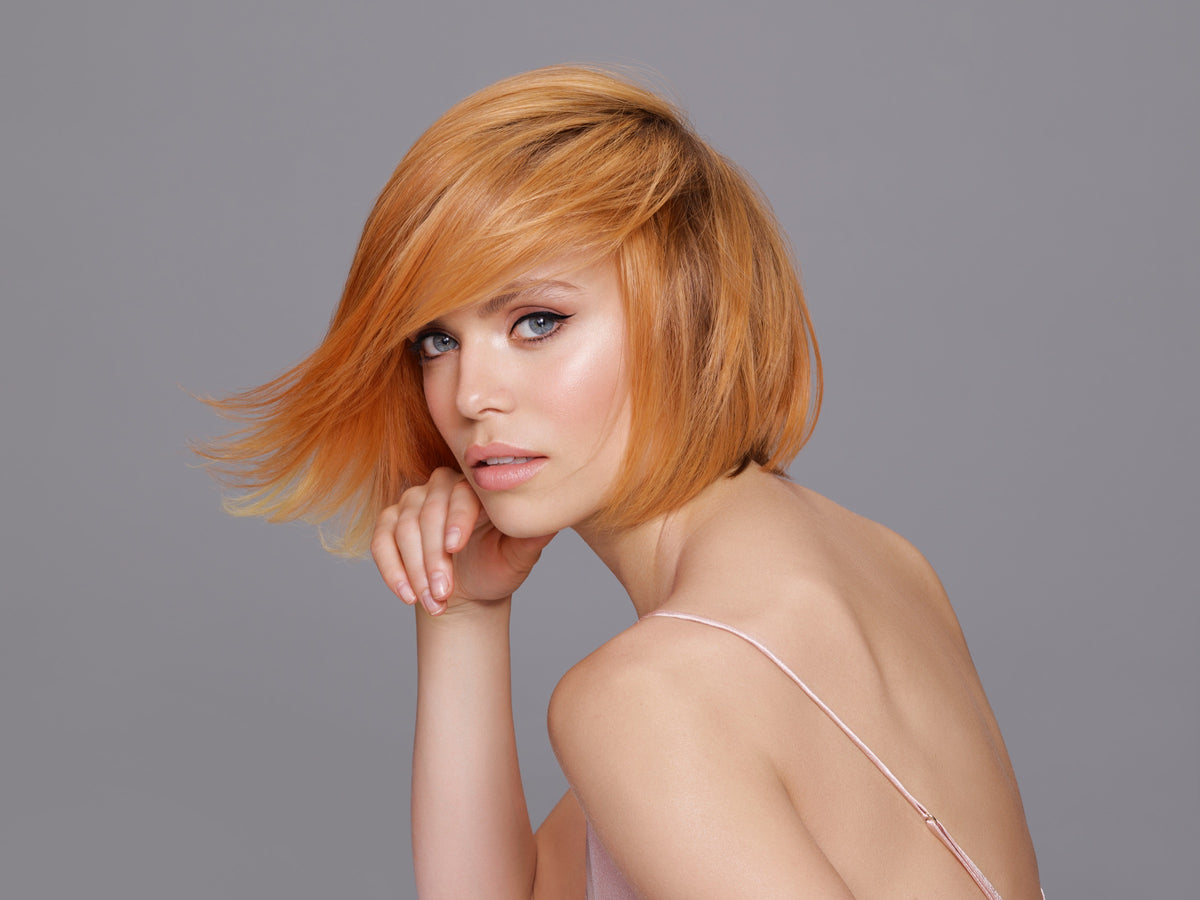 Modelo con corte bob cobrizo de color intenso sobre fondo gris, trabajo de color Framesi